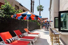 a patio with orange and blue chairs and umbrellas