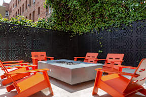 an outdoor seating area with orange chairs and a fire pit