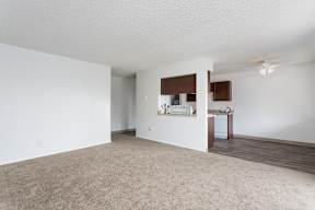 an empty living room with white walls and a kitchen