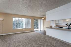 an empty living room with a kitchen and a door to a patio