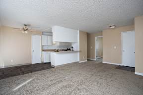 an empty living room and kitchen with a ceiling fan