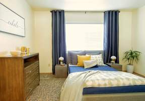A bedroom with a bed, nightstand, and a dresser with a lamp on top.