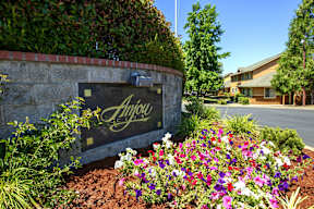 A sign that says Anjoy is surrounded by flowers.