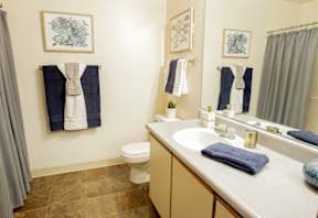 A bathroom with a toilet, sink, and towels.
