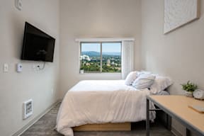 A bedroom with a large bed and a flat screen TV mounted on the wall.