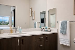 A bathroom with a sink, mirror, and cabinets.
