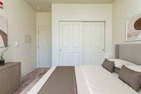 A bedroom with a bed, dresser, and two doors.