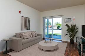 A living room with a couch, a coffee table, and a painting on the wall.