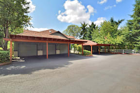 A large building with a red roof and a parking lot in front.