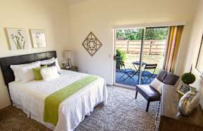 A bedroom with a large bed and a chair.