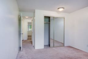 an empty bedroom with mirrored closet doors and a carpeted floor
