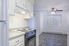 a kitchen with white cabinets and a stove and a ceiling fan