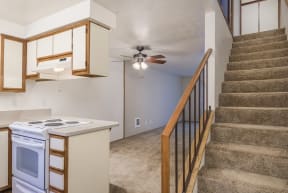 the kitchen is next to the stairs in a home with a ceiling fan