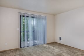 the spacious living room of an apartment with a large window and a sliding glass door