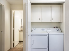 an empty laundry room with white appliances and white cabinets