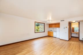 the living room and kitchen of an empty house with wood floors and a window