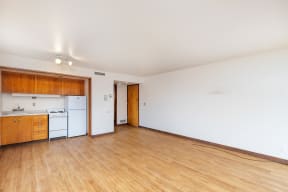the living room of an empty apartment with wood flooring and a kitchen