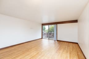 an empty living room with wood floors and a sliding glass door