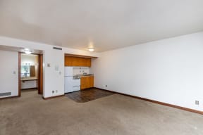the living room and kitchen of an empty house with white walls and a carpet floor