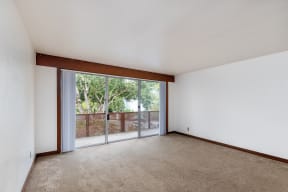 an empty living room with a sliding glass door to a balcony