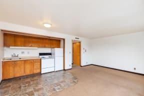 the living room and kitchen of an empty house with white appliances and wooden cabinets