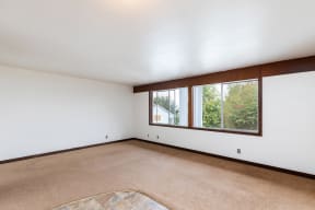 an empty living room with a large window and white walls