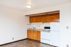 an empty kitchen with white appliances and wood cabinets