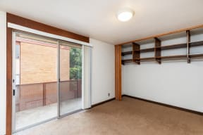 a bedroom with a sliding glass door and a window with shelves on the wall