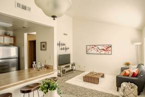 A living room with a grey couch and a painting on the wall.