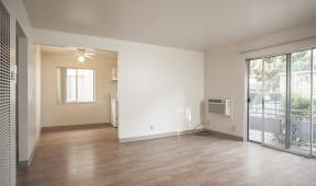 an empty living room with a sliding glass door to a balcony