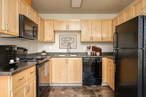 A kitchen with black appliances and wooden cabinets.