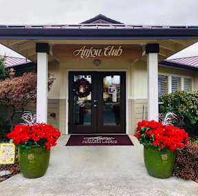 The Anyou Club has a welcoming entrance with two green vases filled with red flowers.