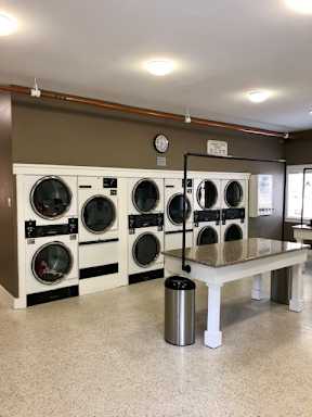 A laundromat with a row of washers and a clock on the wall.