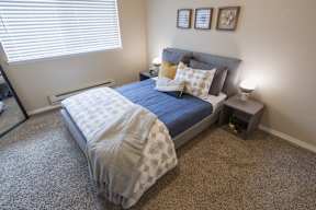 A bedroom with a bed, nightstand, and window.