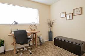 A room with a desk, chair, and a bench.