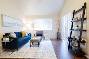 A living room with a blue couch, a coffee table, and a painting on the wall.