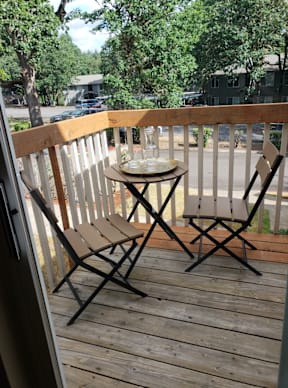 A table with two chairs on a wooden deck.