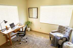 A room with a desk, chair, and a couch.