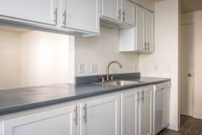 A kitchen with white cabinets and a grey countertop.