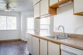 A kitchen with a white dishwasher and a window.