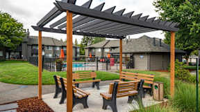 A wooden bench under a pergola in a park.