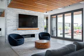 this living room has a large stone fireplace with a wooden mantle and a large flat screen tv