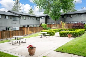 an outdoor patio with picnic tables in front of an apartment building