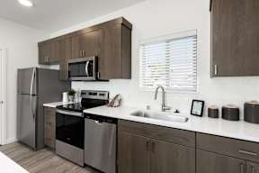 A modern kitchen with dark wood cabinets and stainless steel appliances.