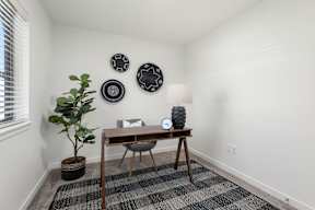 A bedroom with a table, a plant, and three decorative plates on the wall.
