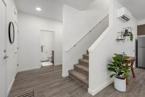 A white staircase with a wooden handrail and a potted plant on the landing.