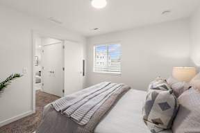 A bedroom with a bed, pillows, and a plant.