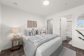 A bedroom with a large bed and a nightstand with a lamp.
