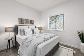A bedroom with a large bed and a window with blinds.