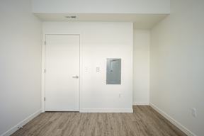 A white door is on the left and a white wall with a mirror on the right.